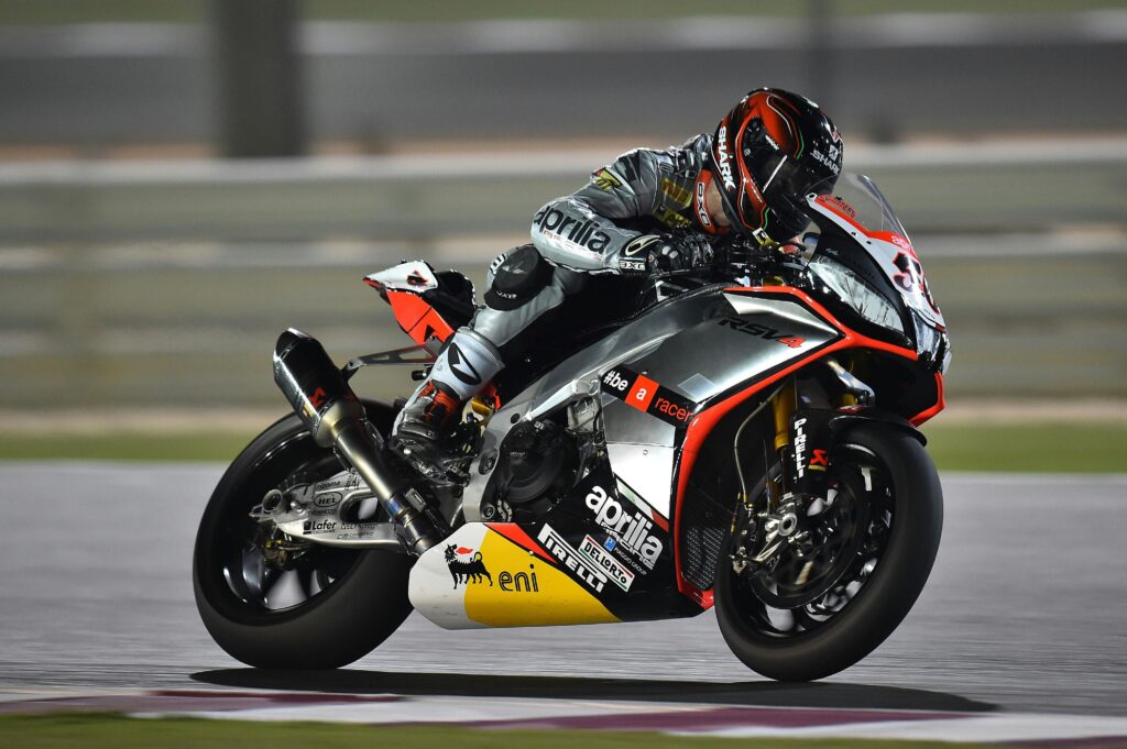 A professional motorbike racer leans into a turn during a high-speed race, showcasing agility and precision.