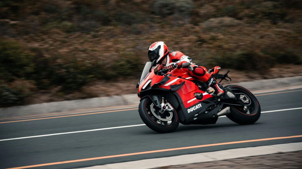 An intense action shot of a Ducati sports bike racing on scenic roads in Rooi-Els, South Africa.